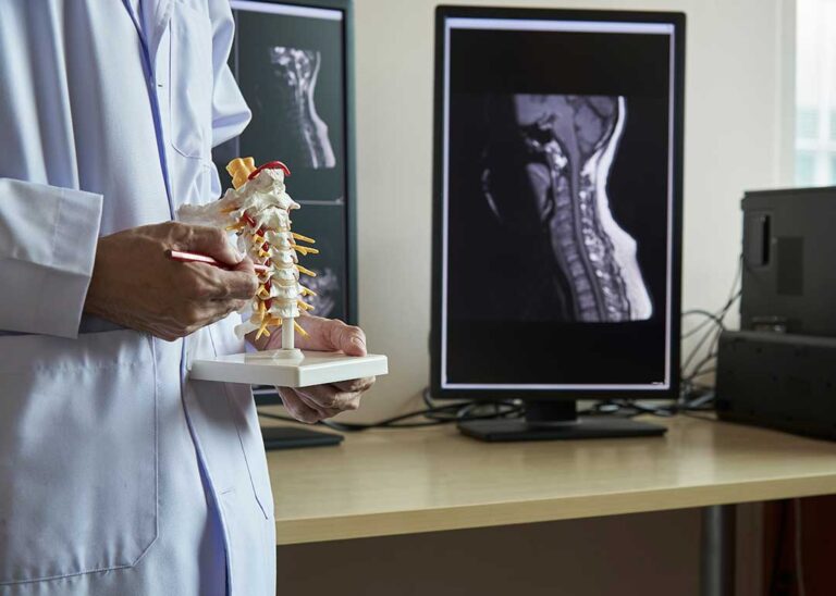 Person seated at a home workstation with a raised screen, relaxed shoulders, and neutral neck posture.